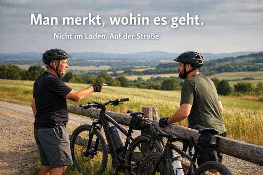 Zwei Männer mit E-Bikes auf einer Schotterstrecke in ländlicher Landschaft – E-Bike Alltag, Fahrgefühl und Freiheit