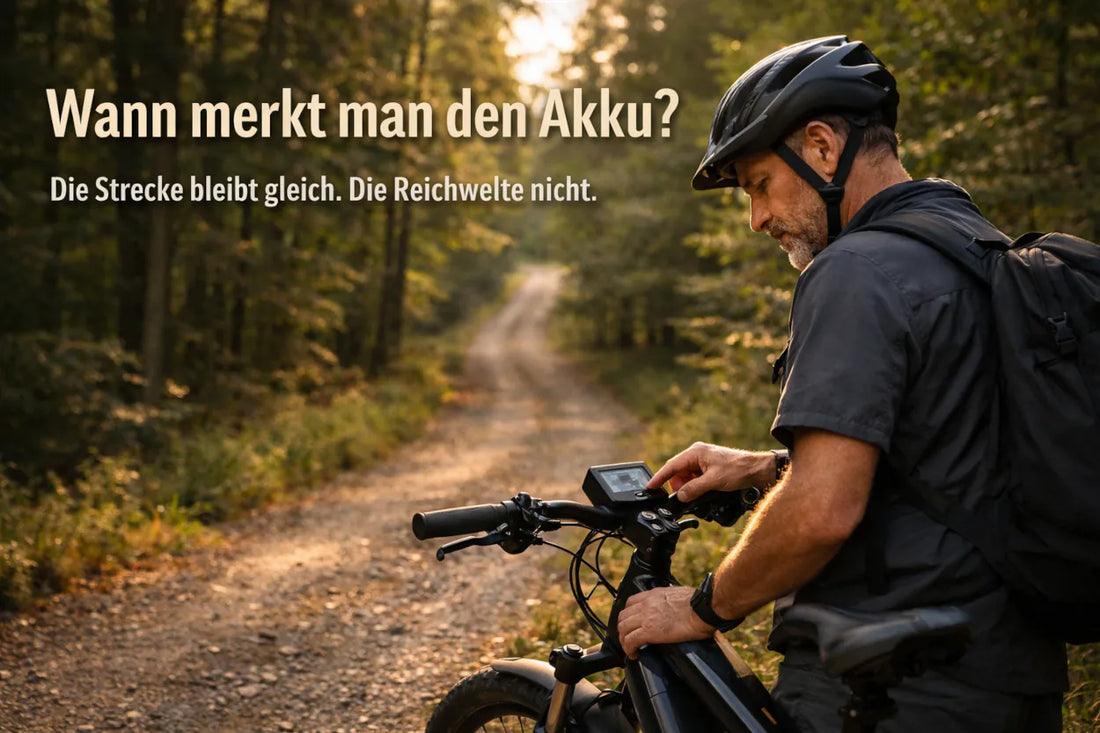 E-Bike Fahrer schaut auf das Display seines Fahrrads auf einem Waldweg und überprüft die Akku-Reichweite während einer Tour