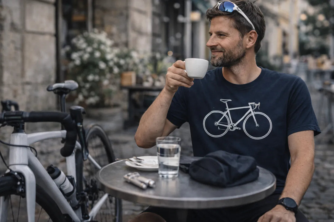 Rennradfahrer sitzt nach der Ausfahrt im Café und trägt navy T-Shirt mit „ICH BIN DER MOTOR“ Roadbike-Design – Geschenkidee für Roadies.