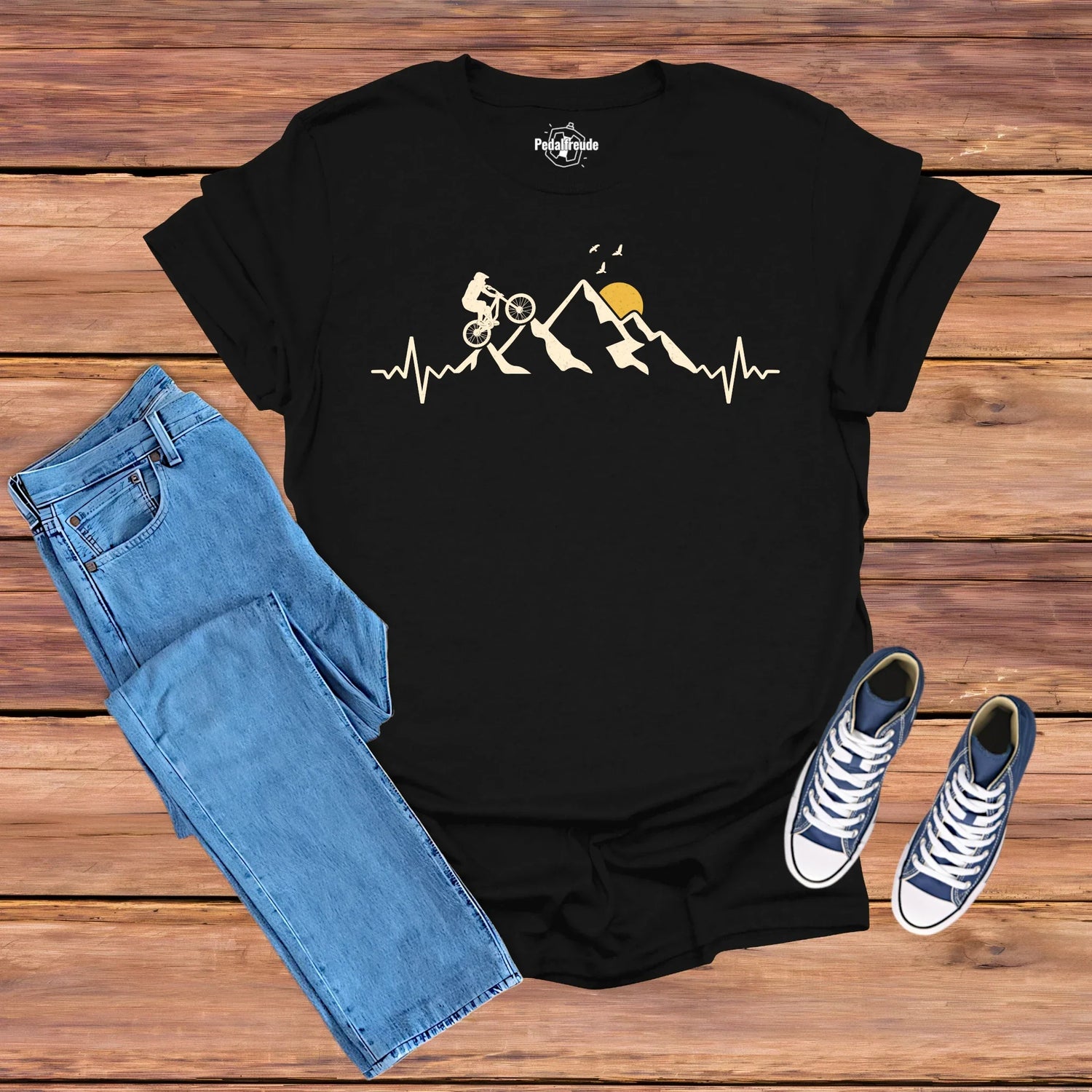 Pedalfreude MTB-Kollektion T-Shirt Mockup in Schwarz mit Herzschlag-Berge-Sonne Design und Mountainbike-Fahrer.