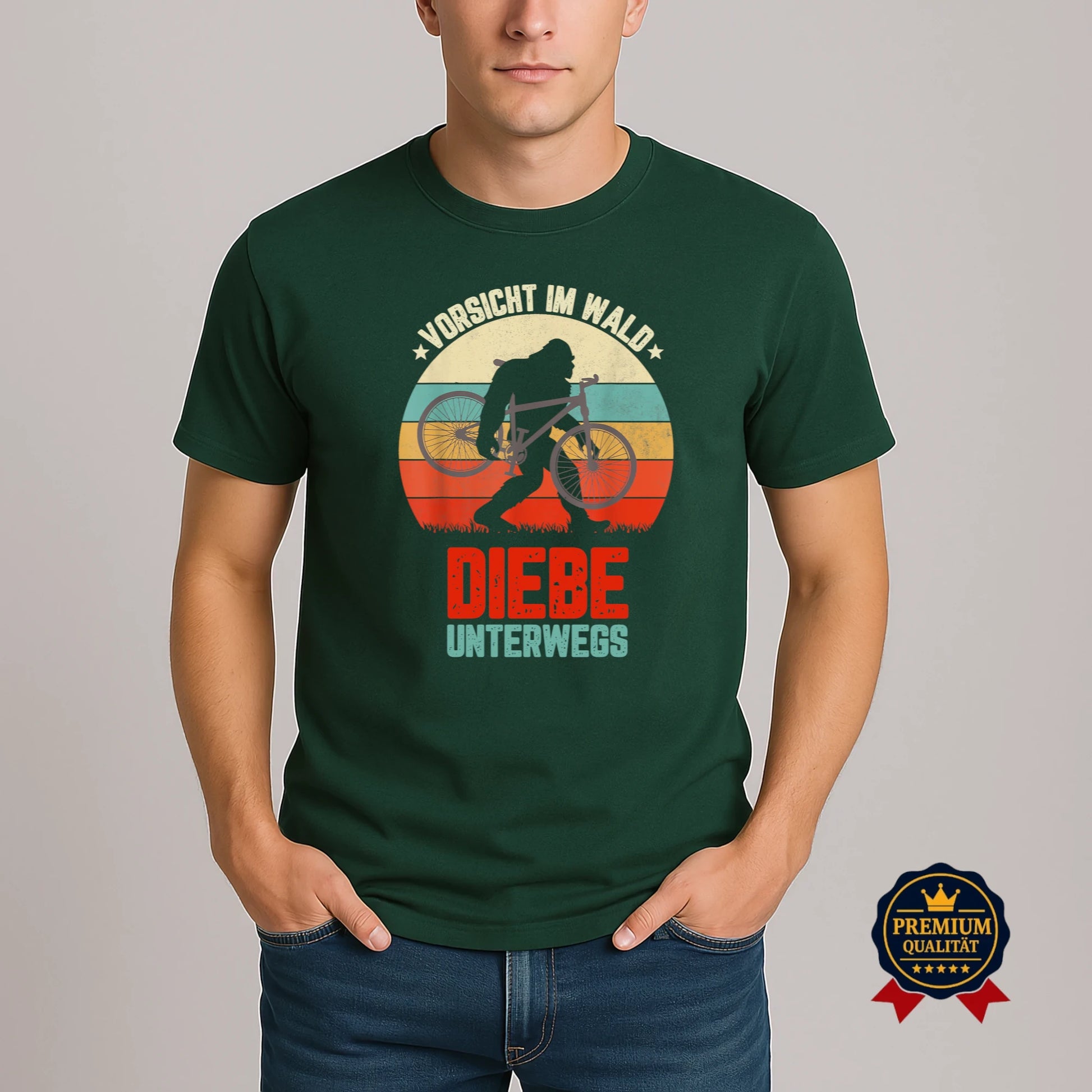 Model trägt grünes Fahrrad-T-Shirt mit Retro-Motiv ‚Vorsicht im Wald – Diebe unterwegs‘ und Bigfoot-Silhouette mit Fahrrad.