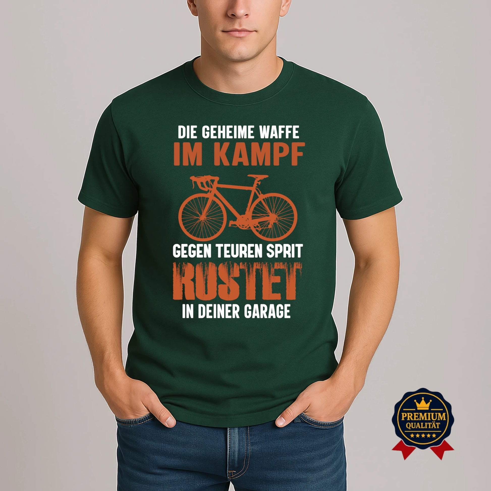 Grünes Rundhals-T-Shirt mit Fahrrad-Design und witzigem Sprit-Spar-Statement 'Die geheime Waffe im Kampf gegen teuren Sprit – rostet in deiner Garage', getragen von Model.