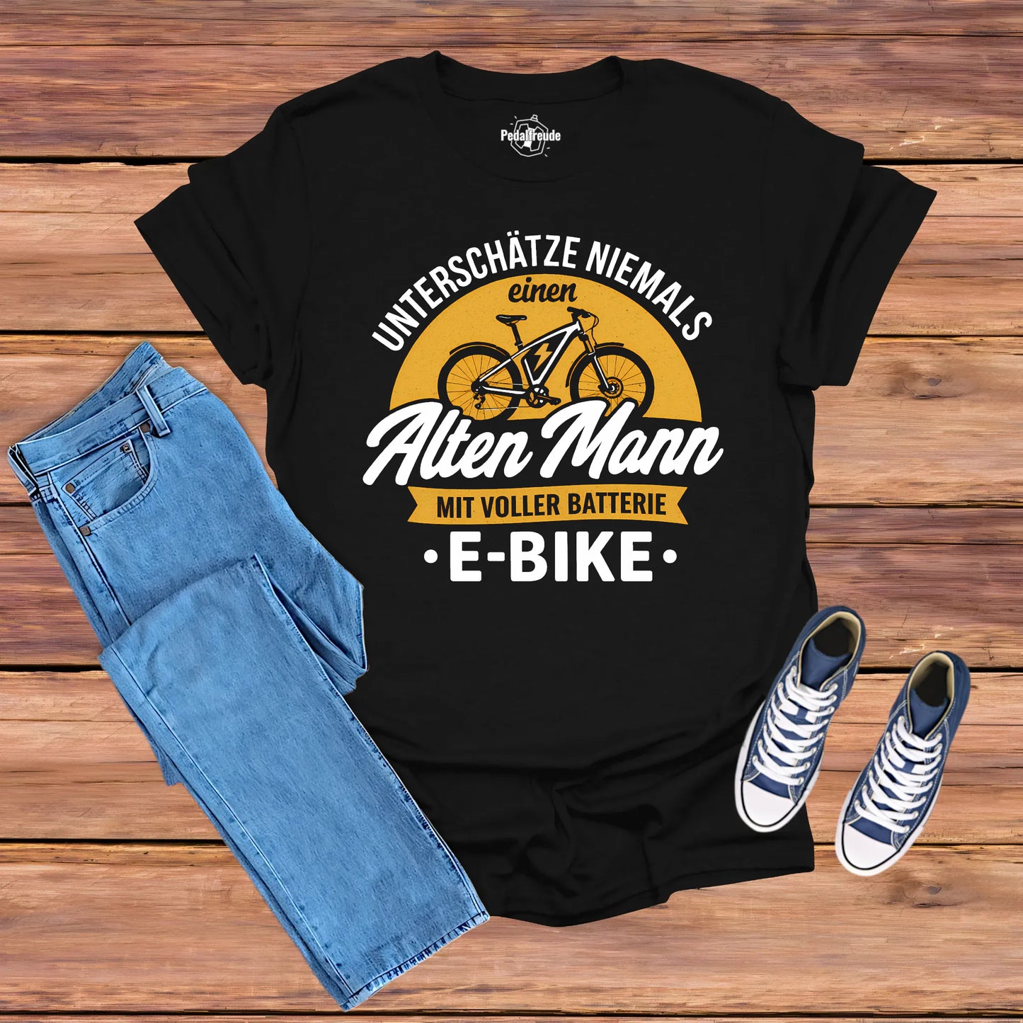 Schwarzes E-Bike T-Shirt Herren „Unterschätze niemals einen alten Mann mit voller Batterie“ – Flatlay mit Jeans und Sneakern