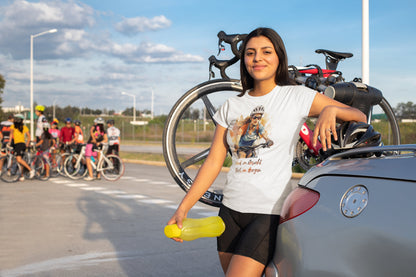 Fahrradfahrerin mit weißem T-Shirt „Wind im Gesicht, Glück im Herzen“ lehnt entspannt am Auto – authentischer Lifestyle-Look für Radfahrerinnen mit Abenteuerlust