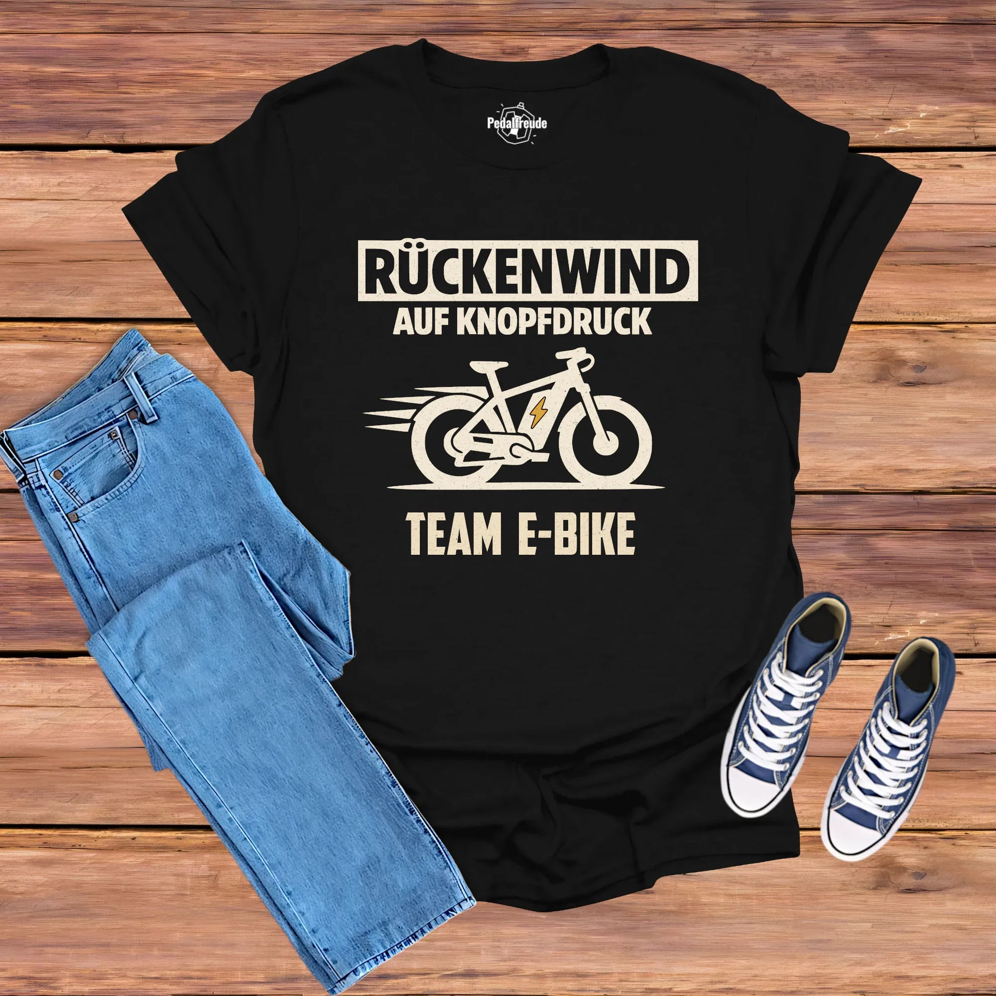 Flatlay: Schwarzes E-Bike T-Shirt „Rückenwind auf Knopfdruck – Team E-Bike“ im Vintage-Look (Pedalfreude)