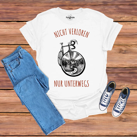 Weißes T-Shirt mit dem Spruch "Nicht verloren, nur unterwegs" und einer stilisierten Fahrrad-Illustration mit Berglandschaft, perfekt für Radfahrer und Abenteurer.